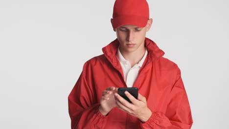 man in red cap and jacket using smartphone