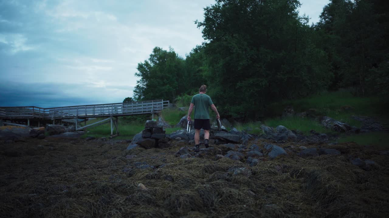 새로 잡은 물고기를 들고 노르웨이 시골에서 산책하는 남자
