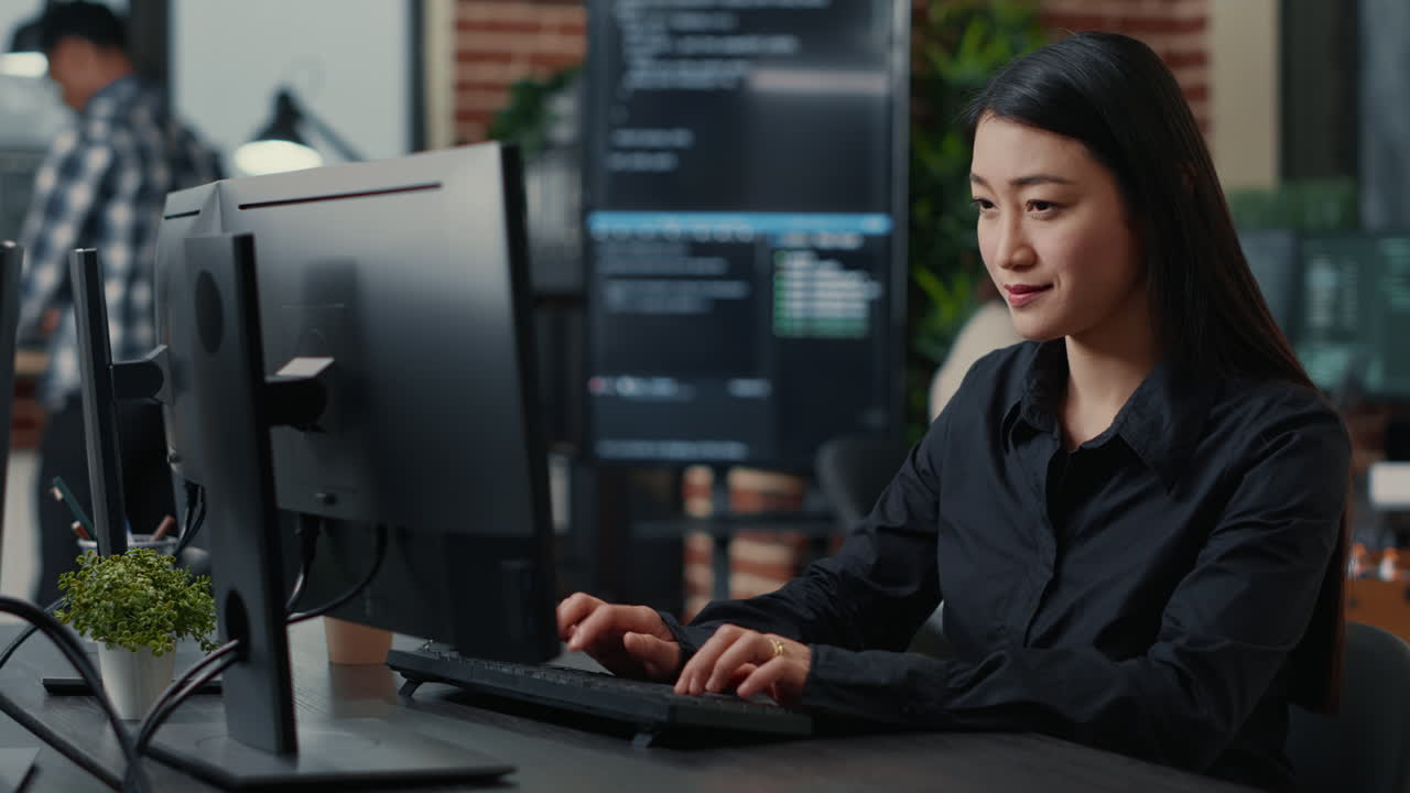 Portrait of smiling asian programer focused on writing code sitting at desk