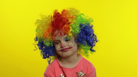 Little-child-girl-clown-in-rainbow-wig-making-silly-faces,-having-fun,-laughing,-dancing.-Halloween