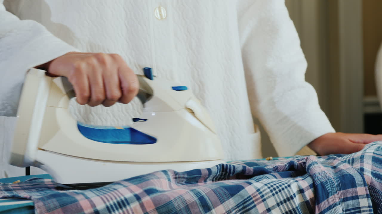 격자 무늬 셔츠를 다림질하는 여자의 손