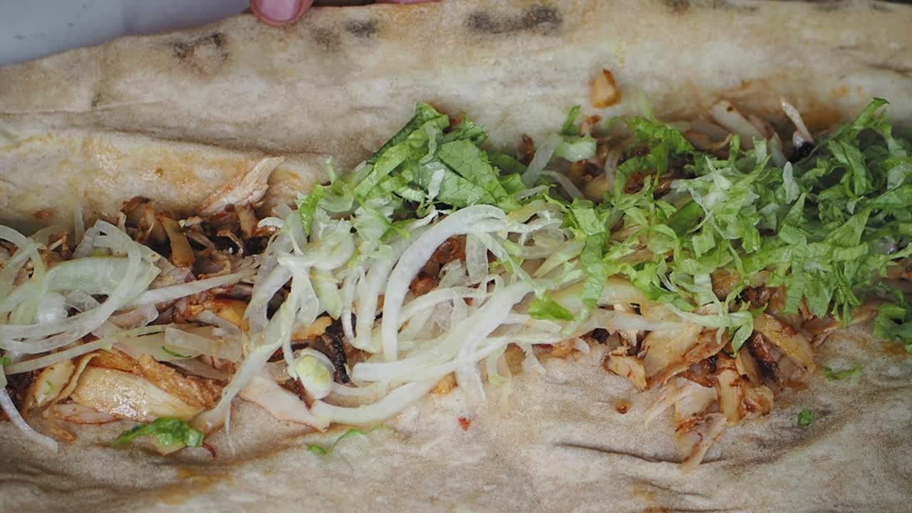Frischen Salat zu einem Döner-Wrap hinzufügen