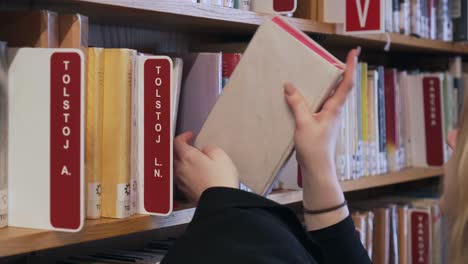 La-Mujer-Está-Llevando-Libros-A-Las-Estanterías-De-La-Biblioteca,-Detalle-De-Sus-Manos