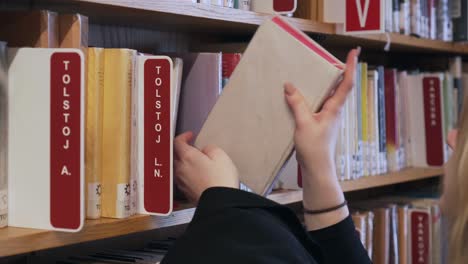 la mujer está llevando libros a las estanterías de la biblioteca, detalle de sus manos