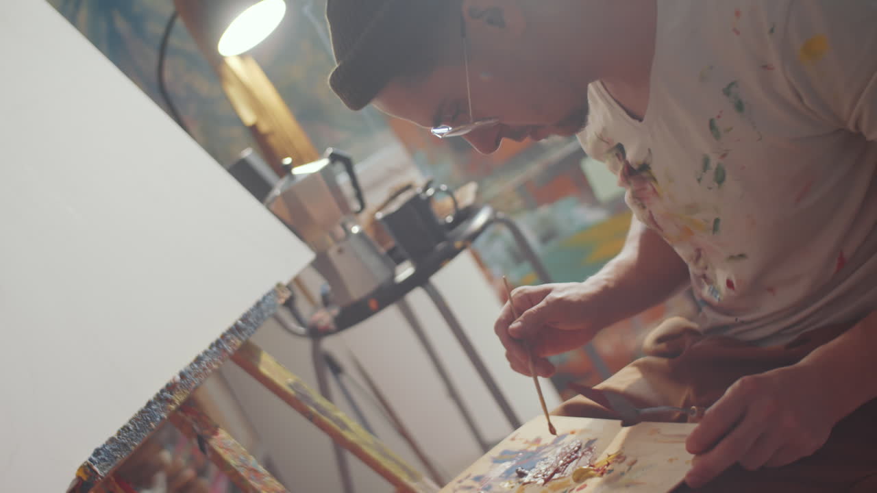 화가 가 페인트 색 을  ⁇ 어서 팔레트 에 브러시 를 쓴다