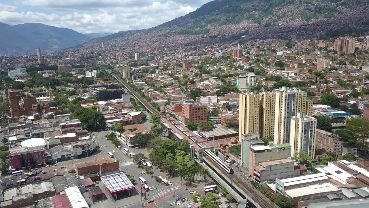 Aerial view showcasing a train traveling through the bustling center of downtown Medellín, surrounded by urban architecture