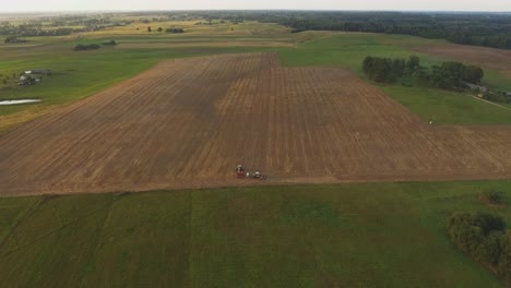 Aerial-Flying-Towards-Heavy-Agricultural-Machinery-Tractors-In-Agricultural-Fields-On-A-Sunny-Summer-Evening