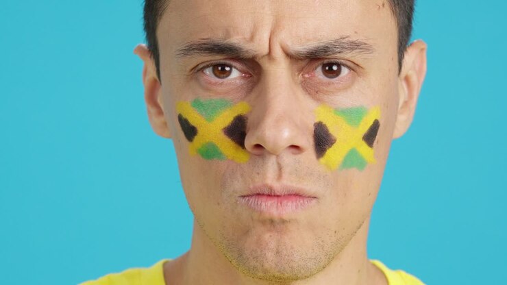 Serious man with a jamaican flag painted on the face