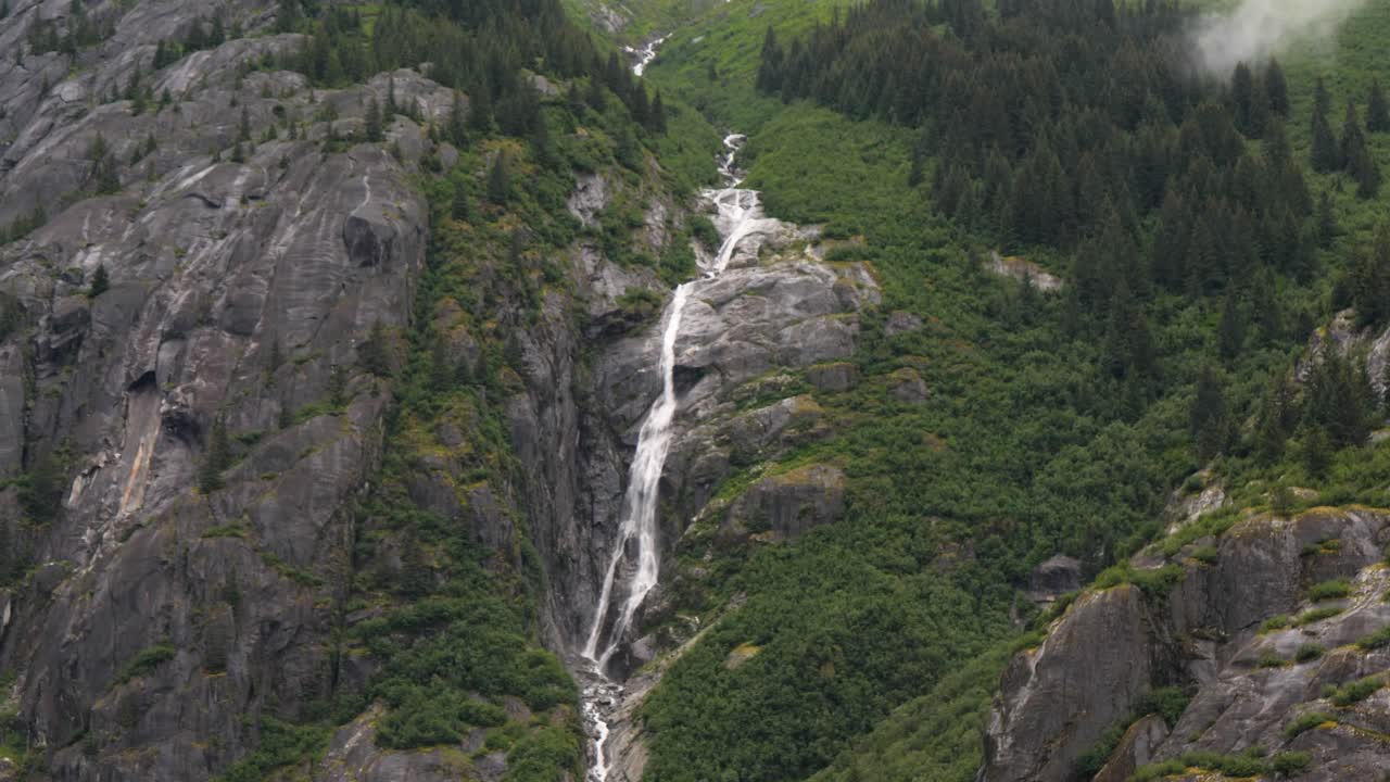 Waterfall along the granite steep wall of the mountain at Endicott Arm Fjord, Dawes Glacier, Alaska.