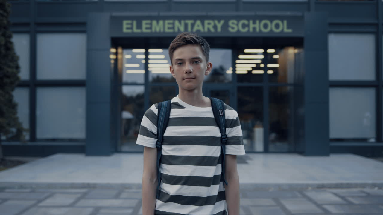 학교 마당에 서 있는 심각한 십대 소년. 긴장된 학교 소년이 혼자 포즈를 취하고 있다.