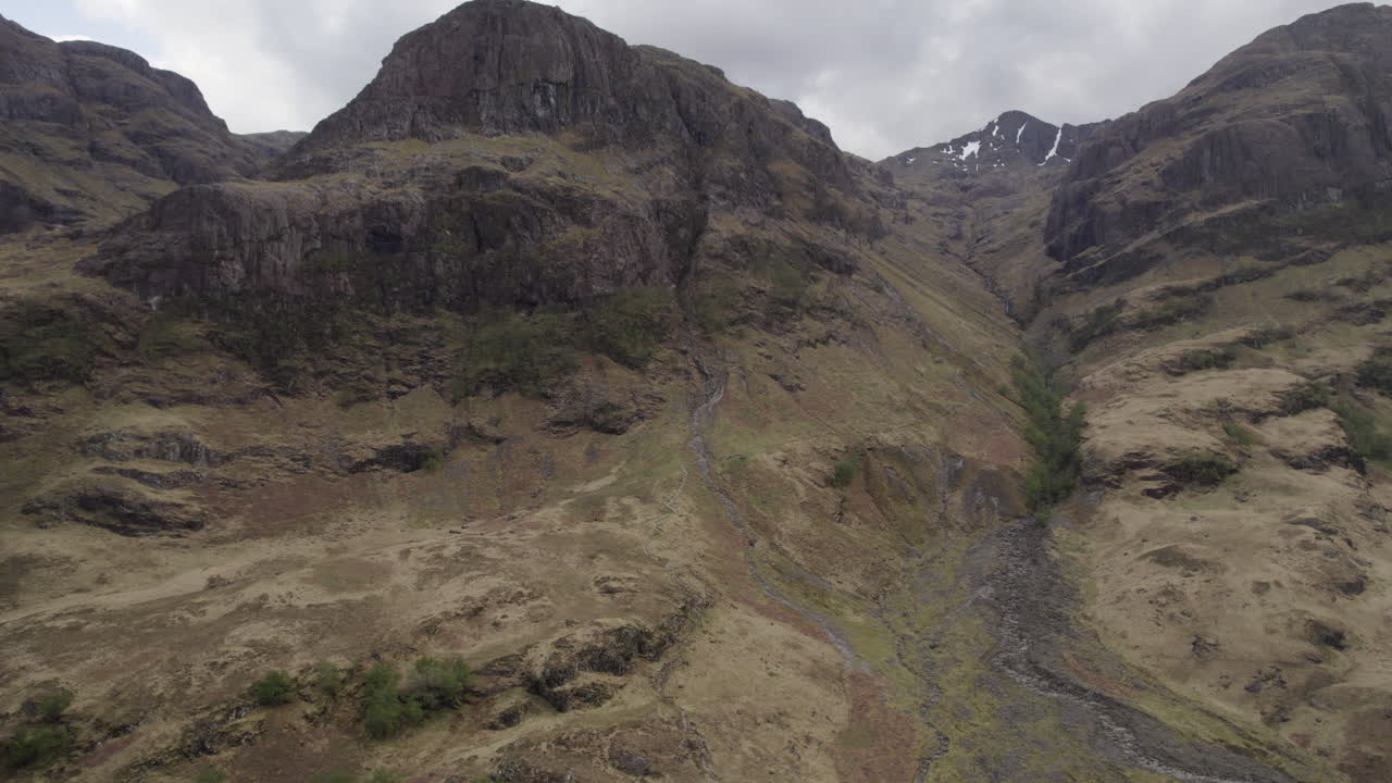 drone aéreo inclinado hacia arriba revelación de la montaña las tres hermanas en glencoe en las tierras altas de escocia