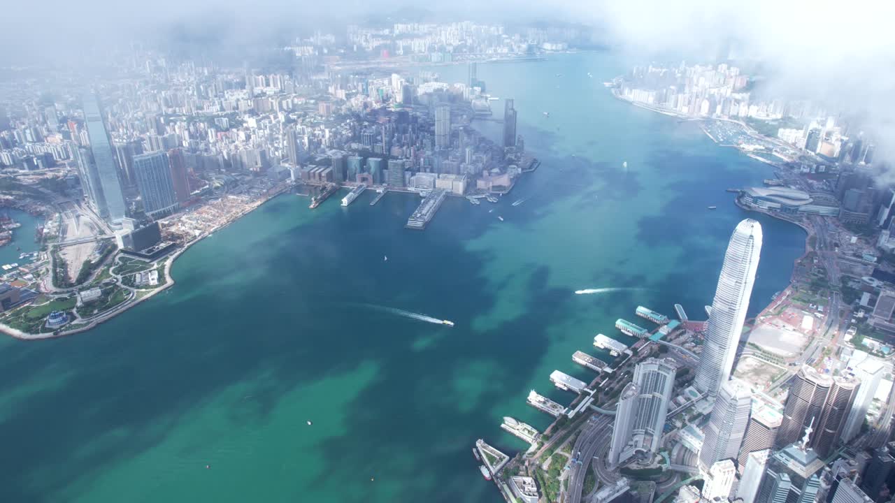 Epic aerial view of the Victoria Harbour in a clear day, with thick cloud and sunlight