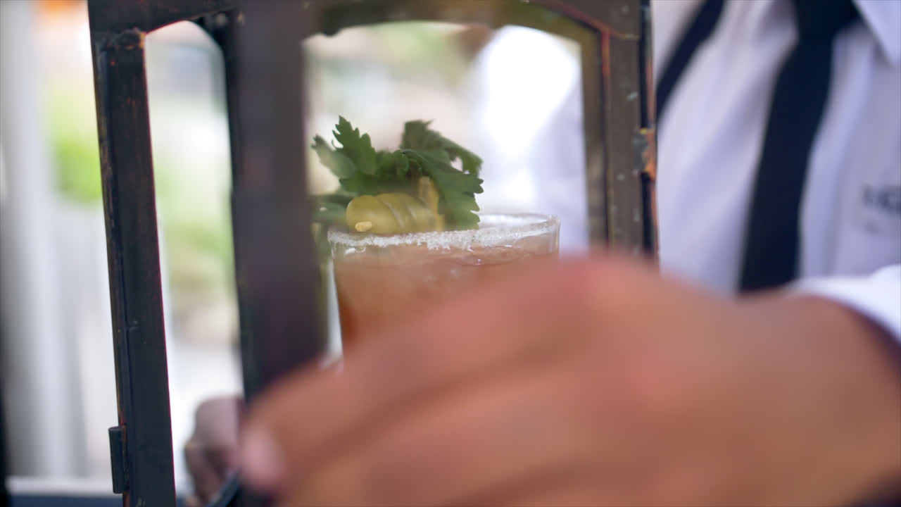 Close slomo of Bloody Mary drink being locked into glass cage at bar