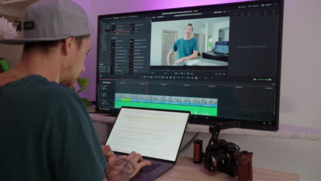 Hombre-Joven-Creativo-Escribiendo-En-Una-Computadora-Portátil-Con-Davinci-Resolve-2-En-Un-Monitor-Más-Grande