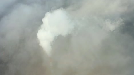 smoke from a power station chimney rising from a low, creeping fog. drone view