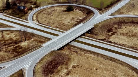 Aerial-establishing-above-roundabout-countryside-highway-in-dry-fields-cars-slow-by