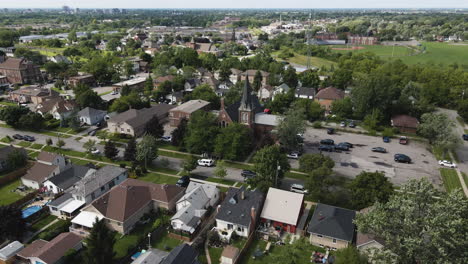 Aerial-dolly-push-in-above-calm-suburban-church-surrounded-by-lush-green-trees-and-yards