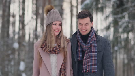 in the winter snowy forest, young men and women dressed in coats and scarves are walking and having fun. loving couple spend together valentines day.