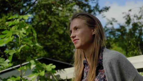 Beautiful-young-woman-stares-peacefully-in-outdoor-garden,-low-angle