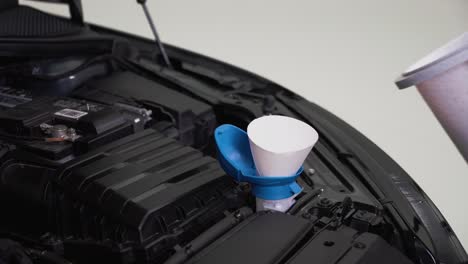 a man refilling windscreen wiper fluid in his car