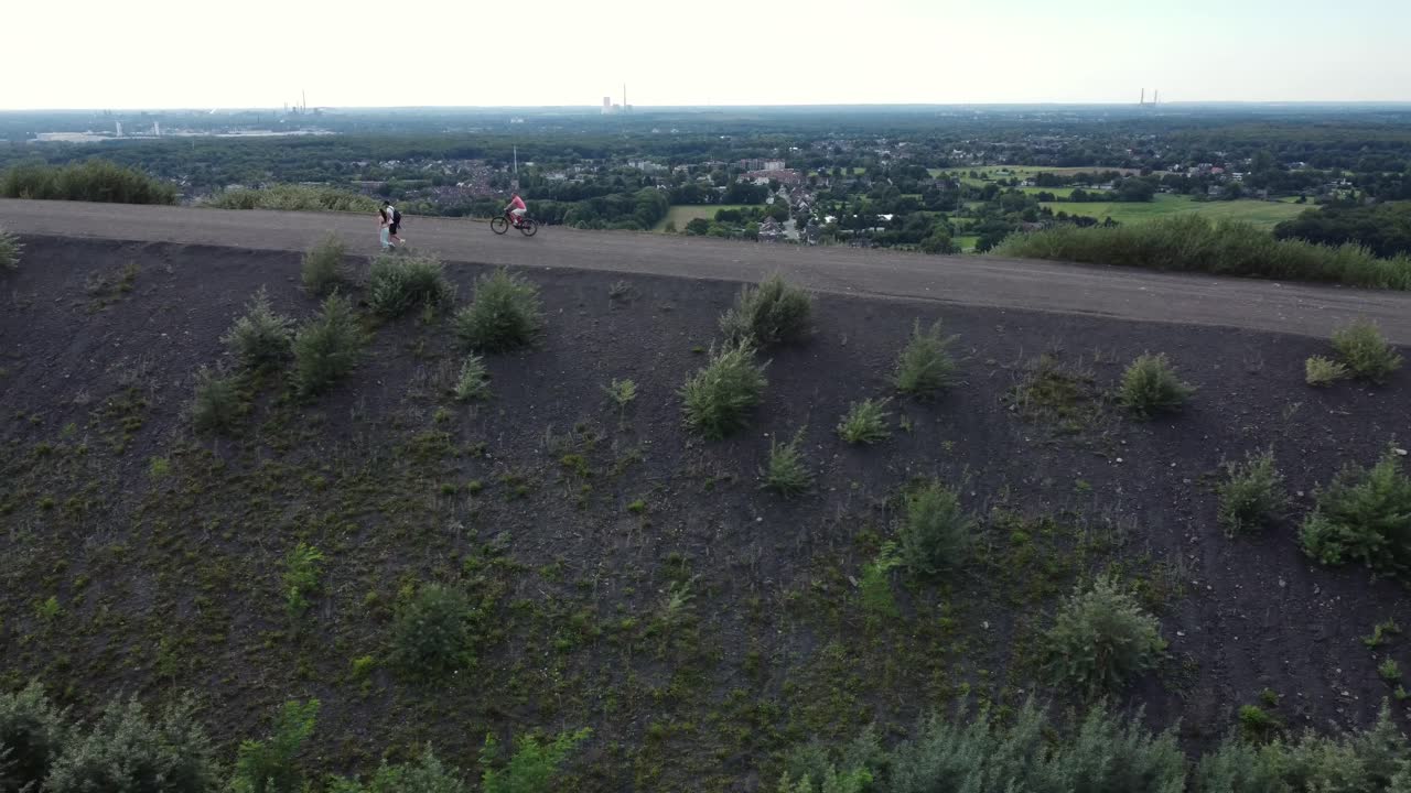 People Cycling on a Hill in a Rural Landscape