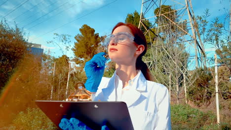 una joven científica en un arroyo, con gafas de protección y una bata de laboratorio, tomando notas en un clipboard