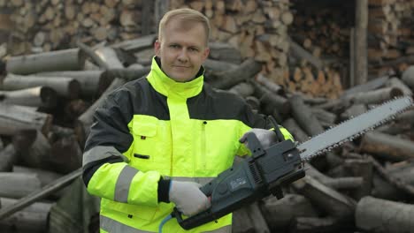 holzfäller in reflektierender jacke. holzfäller mit elektrischer kettensäge. gesägte stämme, brennholz, sägewerk