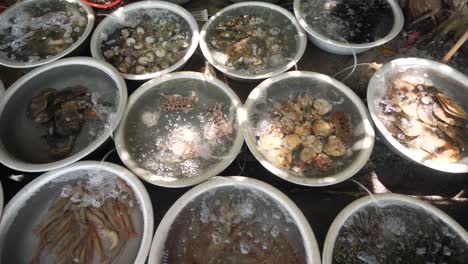 different kinds of fresh catch alive seafoods inside the basins in open market.