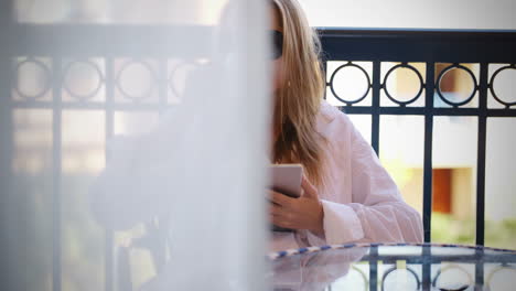 mujer sentada leyendo una tableta pc en un balcón
