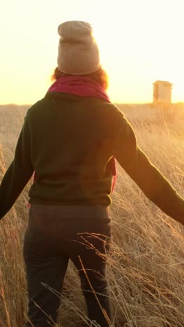 woman walking through a golden field at sunset