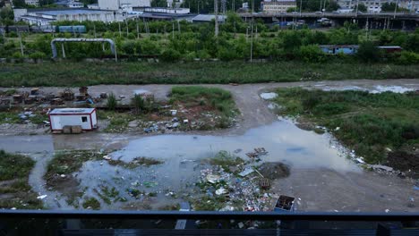 pollution with a lot of garbage, plastic and dirty water in industrial area near city