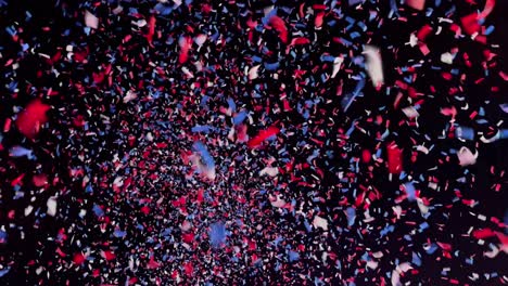 Thousands-of-red,-white,-and-blue-confetti-pieces-falling-from-the-night-sky---background