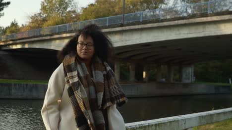 woman standing ouside in the cold autumn weather in front of a bridge and canal