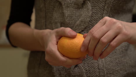 mujer pelando una naranja, mandarina cerca de tiro de manos