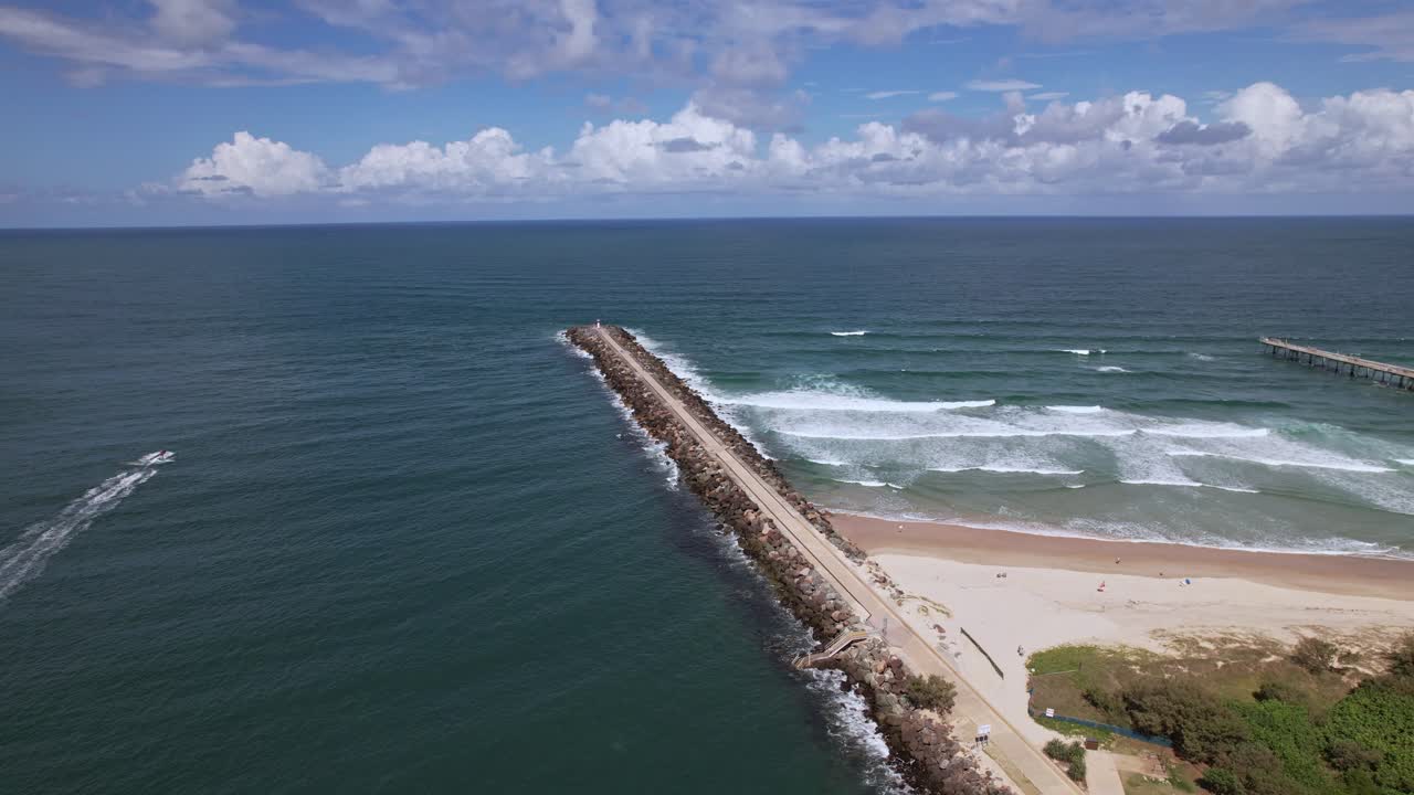 Stone Jetty At The Spit Gold Coast Stretching Into The Ocean. The Spit Dog Beach In Queensland, Australia. aerial shot, sideways panning