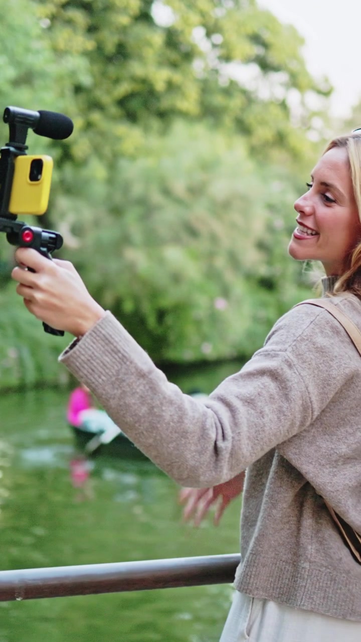 Donna vlogger felice che registra un video con lo smartphone al parco