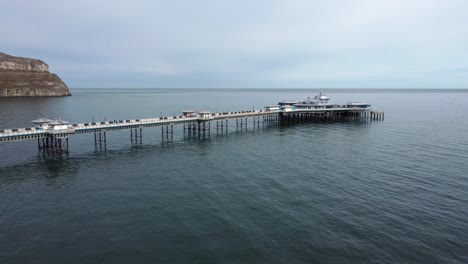 Elegant-stretching-Victorian-Welsh-Llandudno-pier-aerial-view-long-forward-move-on-quiet-morning