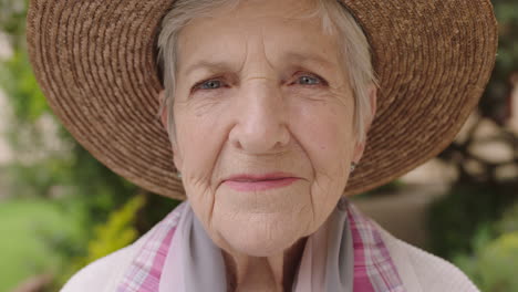 Primer-Plano-Retrato-De-Una-Anciana-Mirando-La-Cámara-Sonriendo-Feliz-Usando-Sombrero-Disfrutando-Del-Soleado-Jardín-Al-Aire-Libre