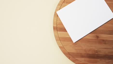 Video-of-book-with-white-blank-pages-and-copy-space-on-wooden-chopping-board-and-yellow-background