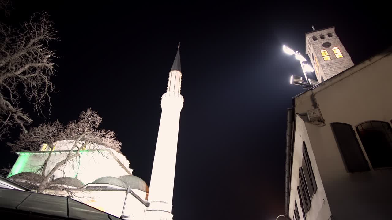 Dettaglio architettonico della vecchia torre dell'orologio e del minareto della moschea Gazi Husrev beg di notte a Sarajevo, Bosnia ed Erzegovina