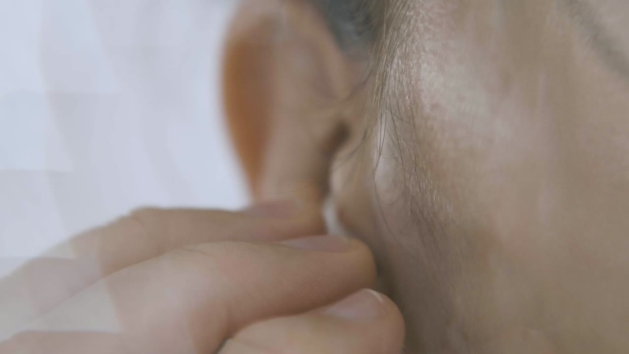detalle de una oreja y una mano e inserta un capó de las cápsulas de aire, cámara lenta y con lente caleidoscopio, efecto caleidoscopio, mágico