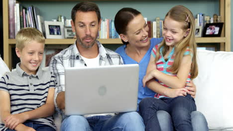 cute family using laptop sitting on the couch