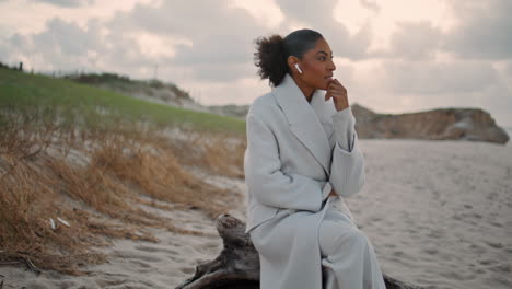 Serene-tourist-talking-phone-at-ocean-shore.-Calm-woman-using-earphones-speaking