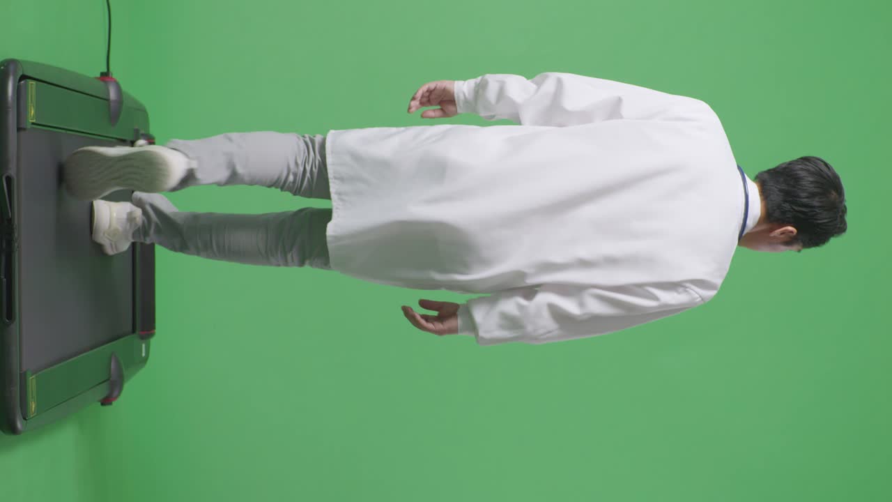 스테토스코프를 가진 아시아 남성 의사가 병원에서 녹색 화면 배경에서 돌아다니고 있습니다.