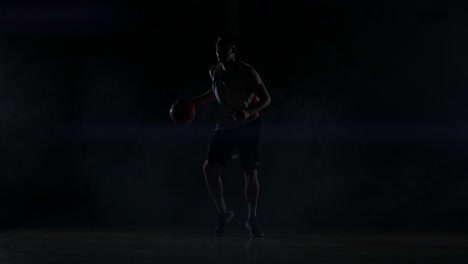 A-basketball-player-dribbles-down-the-court-out-of-the-shadows