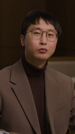 An Asian man in glasses and a suit
