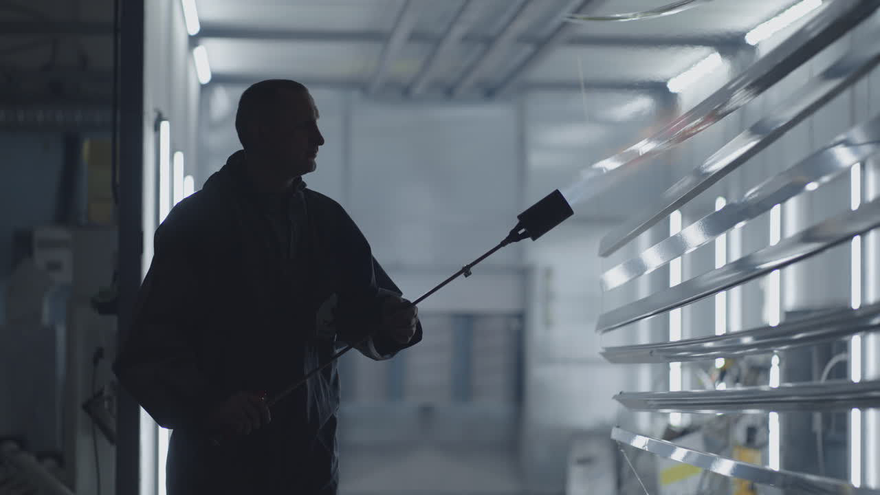 Fire treatment of steel parts in production in slow motion. Preparation for painting metal cleaning by fire at the factory. The worker processes the parts with fire from the burner