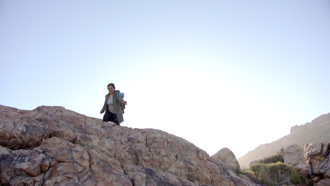Hiking on rocky mountain, woman standing with arms outstretched, enjoying nature, copy space