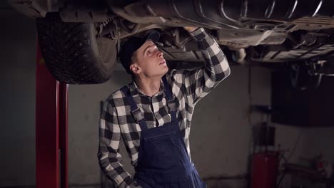 handsome mechanic reparing a car in his workshop.