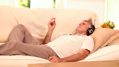 Man-lying-on-sofa-listening-to-music-with-headphones